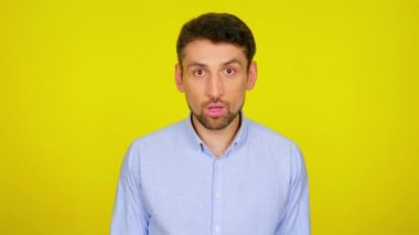 Young man in light blue shirt is surprised and covers his mouth with hands