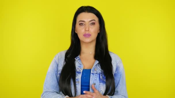 Atraktivní brunetka žena v džínové bundě pózuje a dívá se do kamery — Stock video
