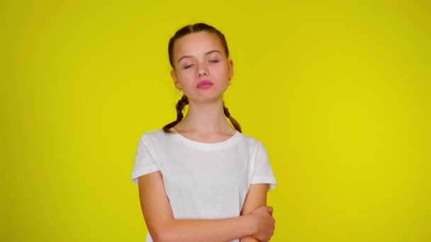 Ένα έφηβο κορίτσι με λευκό μπλουζάκι μασάει τσίχλα και φουσκώνει μια φούσκα. — Αρχείο Βίντεο
