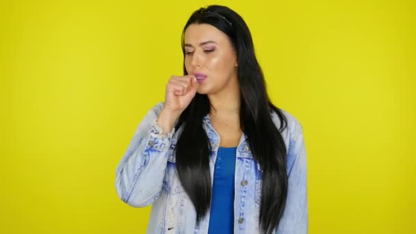 Mujer enferma tose cerrando la boca con el puño sobre un fondo amarillo — Vídeo de stock