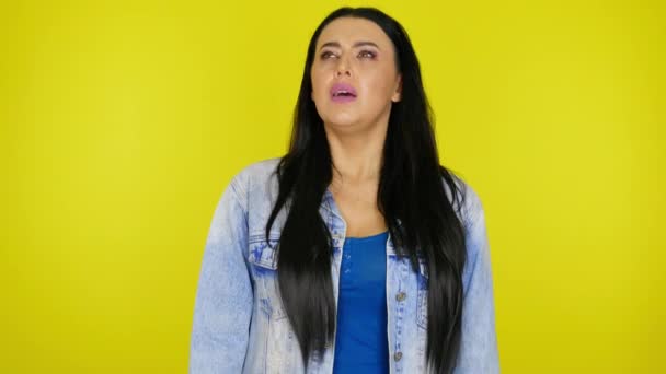 Sick woman sneezes closing her mouth with her fist on a yellow background — Stock Video