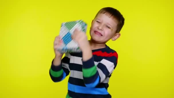 Zabawne dziecko chłopiec tchórze boks z prezentem blisko ucha próbuje zrozumieć, co jest w środku — Wideo stockowe