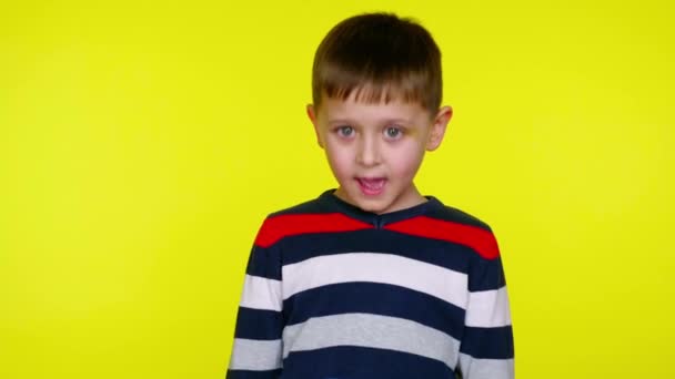 Serious little child boy in a colorful sweater says yes on a yellow background — Stock Video