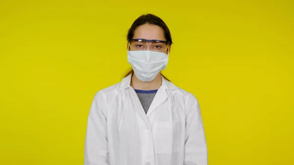 Fiatal orvos védő orvosi maszkban, szemüvegben és fehér köpenyben — Stock Fotó
