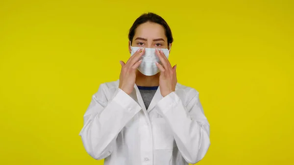 Infectieziekte arts zet een beschermend medisch masker op haar gezicht — Stockfoto