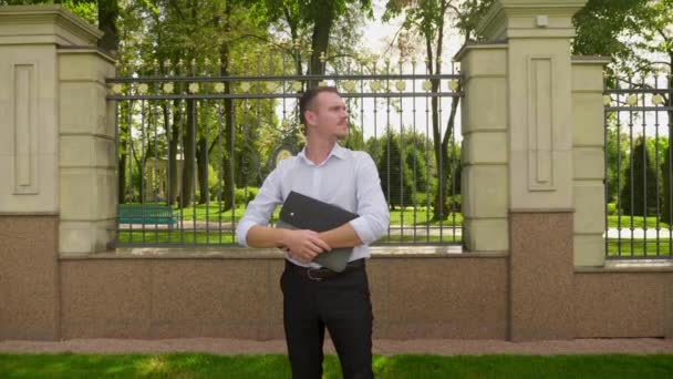 Zakenman startuper praten in het park met een laptop in zijn handen — Stockvideo