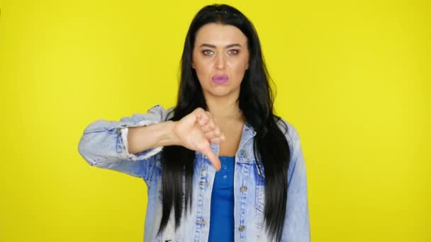 Gloomy woman shows dislike and nods head on a yellow background with copy space — Stock Video