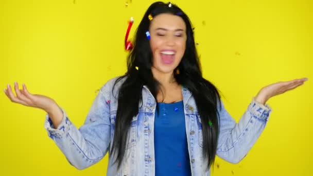 Glada kvinna dansar och konfetti faller på henne en gul bakgrund med copyspace — Stockvideo