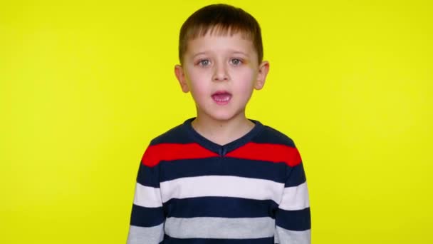 Serious little child boy in a colorful sweater says yes on a yellow background — Stock Video