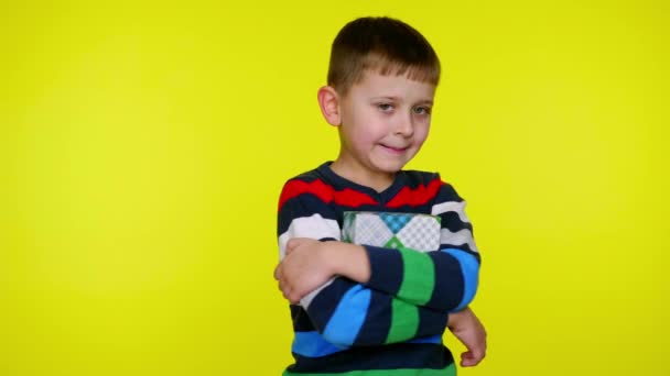 Alegre niño pequeño abrazos caja con regalo sobre fondo amarillo con copyspace — Vídeo de stock