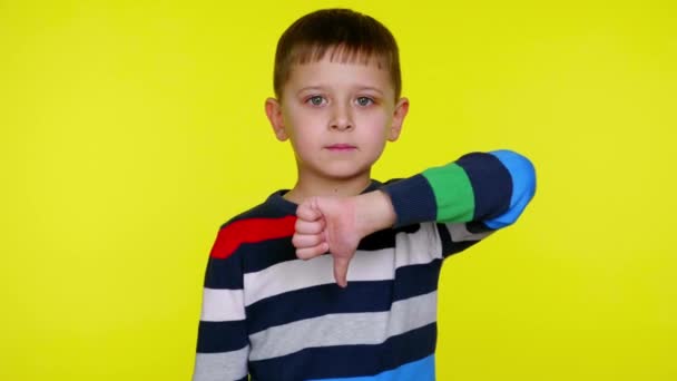 Seriös liten barn pojke höjer handen och visar ogillar på en gul bakgrund — Stockvideo