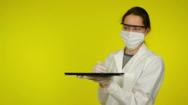 Tıp önlüklü ve koruyucu maskeli kadın, tablet üzerinde holografik teknoloji kullanıyor.
