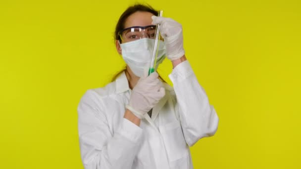 Woman in white medical gown, protective mask is playing with test tube — Stock Video