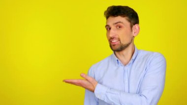 Sakallı adam gülümser ve eli boş bir yerde mesaj ya da ürün gösterir.
