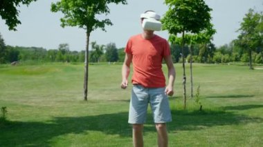 Komik adam parkta sanal gerçeklik kaskıyla dans ediyor.