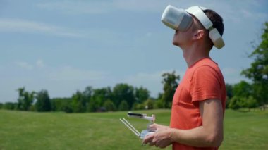 Adam bir kuadrokopteri uzaktan kumandayla kontrol ediyor.