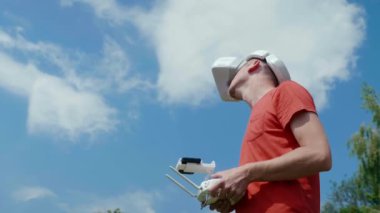 Adam bir kuadrokopteri uzaktan kumandayla kontrol ediyor.