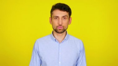 Açık mavi gömlekli üzgün sakallı adam sarı arka planda bir facepalm oluşturuyor.