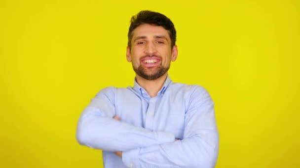 Bearded man turns to the camera, crosses arms and smiles on a yellow background — Stock Video