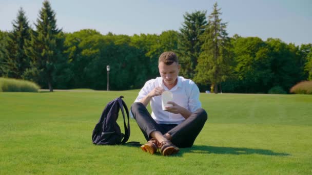 El hombre come comida vegetariana con un paquete ecológico, muestra un gusto y sonríe — Vídeos de Stock