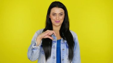 Neşeli kadın ellerini kaldırır ve kalbi parmaklarından katlar ve göz kırpar.