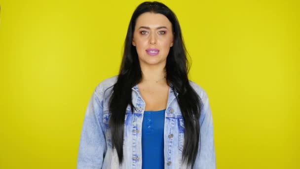 Donna seria con i capelli neri in una giacca di jeans dice sì su uno sfondo giallo — Video Stock