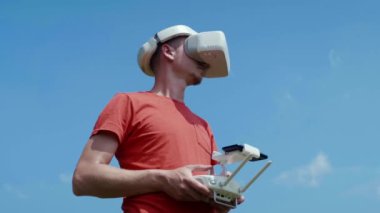 Adam bir kuadrokopteri uzaktan kumandayla kontrol ediyor.