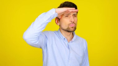 İnsan, elleri alnına dönük bir şekilde, kopyalanmış sarı bir arka plana bakar.