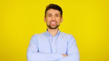 Açık mavi gömlekli yakışıklı sakallı adam gülümsüyor..