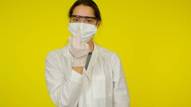 Young infectious disease doctor in a protective medical mask shows a fuck