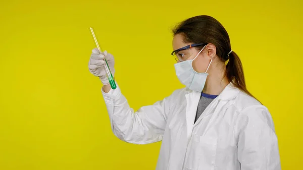 Orvos orvosi maszkban, védőszemüveg és gumikesztyű nézi a tesztek cső — Stock Fotó