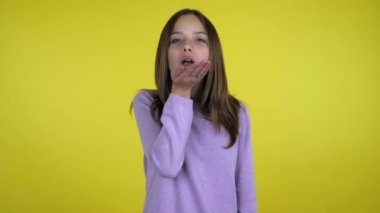 Pembe kazaklı güzel kız sarı arka planda hava öpücüğü yolluyor.