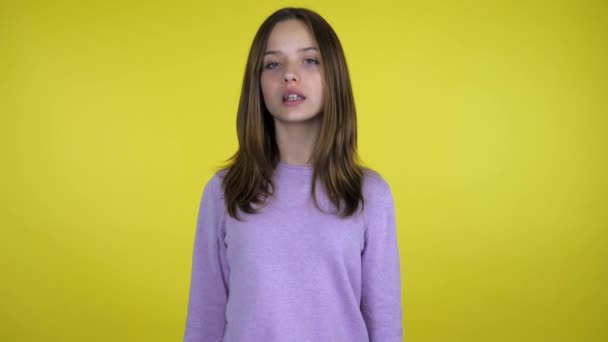 Adolescente chica en un suéter rosa dice que sí en un fondo amarillo con espacio de copia — Vídeo de stock