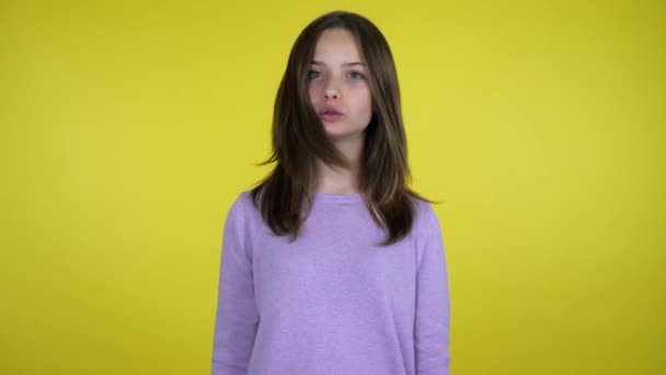 Teen girl in einem rosa Pullover sagt nein auf gelbem Hintergrund mit Kopierraum — Stockvideo