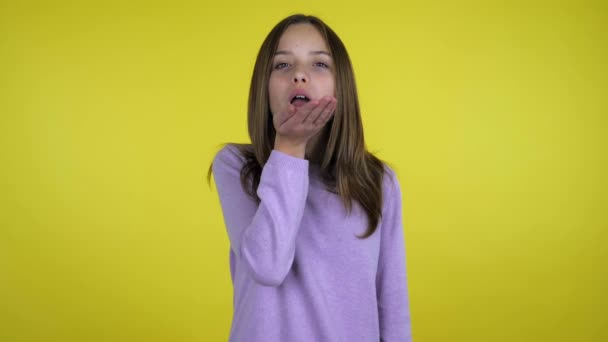 Mooi tiener meisje in een roze trui stuurt een lucht kus op gele achtergrond — Stockvideo