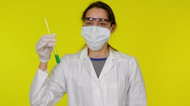 Beyaz elbiseli, koruyucu maskeli genç kadın test tüpüyle dans ediyor.
