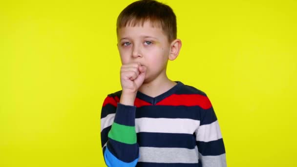 Zieke kleine jongen hoest en bedekt zijn mond met zijn vuist op een gele achtergrond — Stockvideo