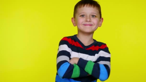 Vrolijke kleine jongen draait naar de camera, kruist armen over borst en glimlach — Stockvideo