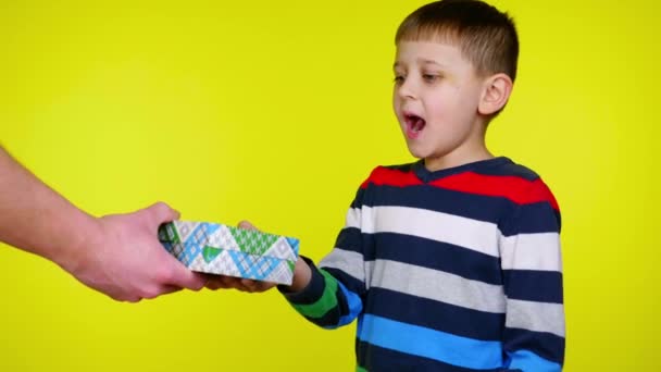 Gelukkige kleine jongen neemt doos met geschenk in zijn handen, opent en is verrast — Stockvideo