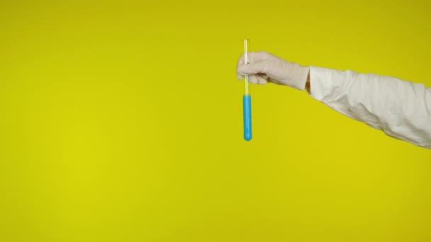Hand i latexhandskens skydd visar ett glasrör med ljusblått ämne — Stockvideo