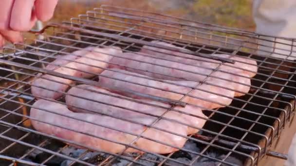 Mannen lukker grillen med pølser på innsiden av naturen – stockvideo