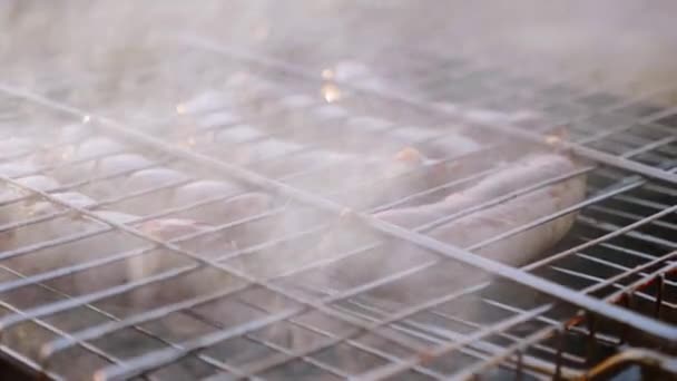 Сосиски крупным планом готовятся в дыму на гриле — стоковое видео