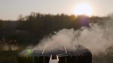 Sosisler, gün batımında ızgarada dumanla pişirilir.