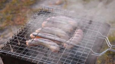 Sosisler ızgarada dumanla pişirilir. Barbeküde yemek pişirme kavramı