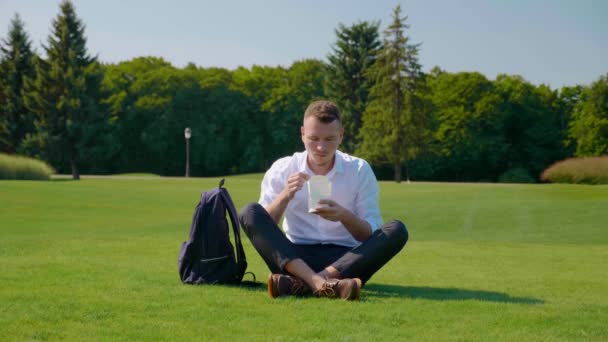 Człowiek zjada swój wegetariański lunch z pakietem ekologicznym, pokazuje podobny i uśmiecha się — Wideo stockowe
