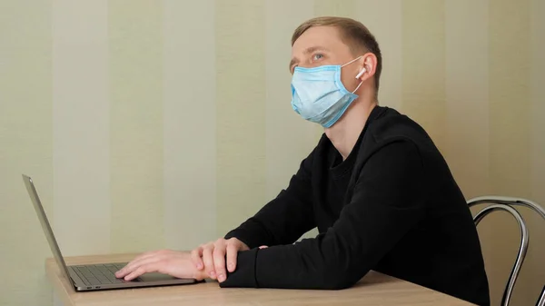 Человек в защитной медицинской маске и беспроводных наушниках в ушах — стоковое фото