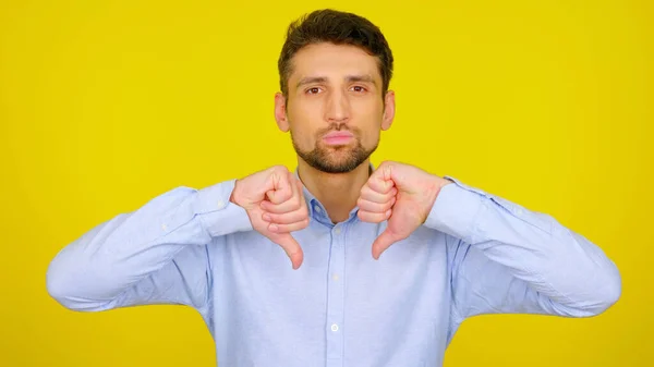 Homem sério mostra antipatia em um fundo amarelo com copyspace — Fotografia de Stock