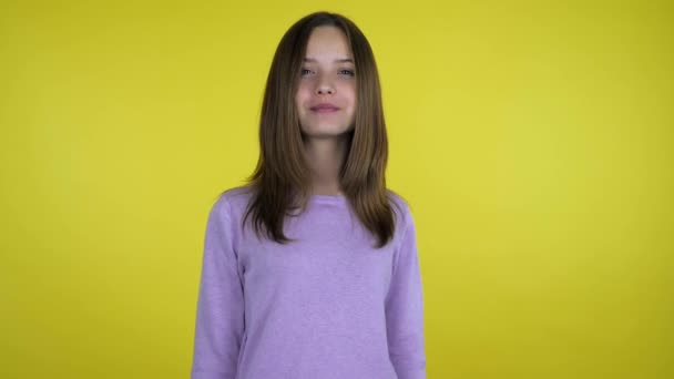 Positive teenager girl in a pink sweater kisses on a yellow background — Stock Video