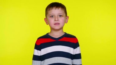 Kızgın küçük çocuk sarı bir arka planda fotokopi alanı olan kameraya hırlıyor.