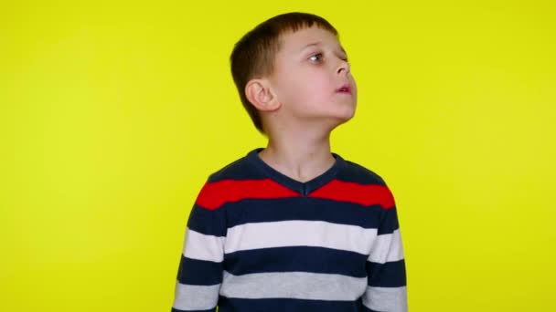 Verward kind jongen kijkt om zich heen en denkt wat te kiezen door het opheffen van de handen omhoog — Stockvideo